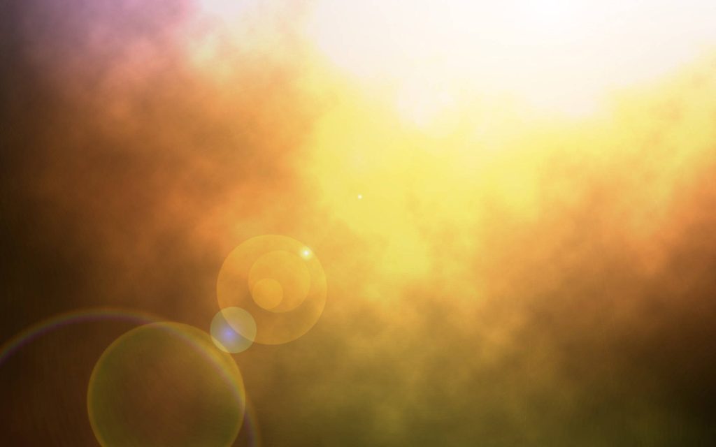 Radiant golden sunlight streaming through soft clouds with warm lens flares abstract background Wallpaper
