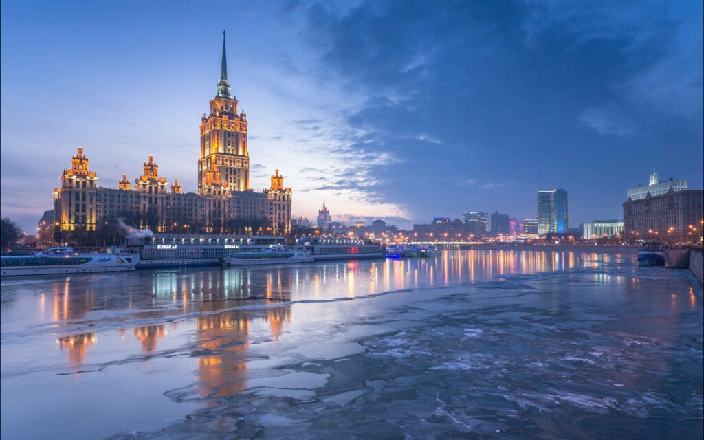 Radisson Collection Hotel Moscow at dusk with illuminated facade reflecting on frozen river skyline Wallpaper