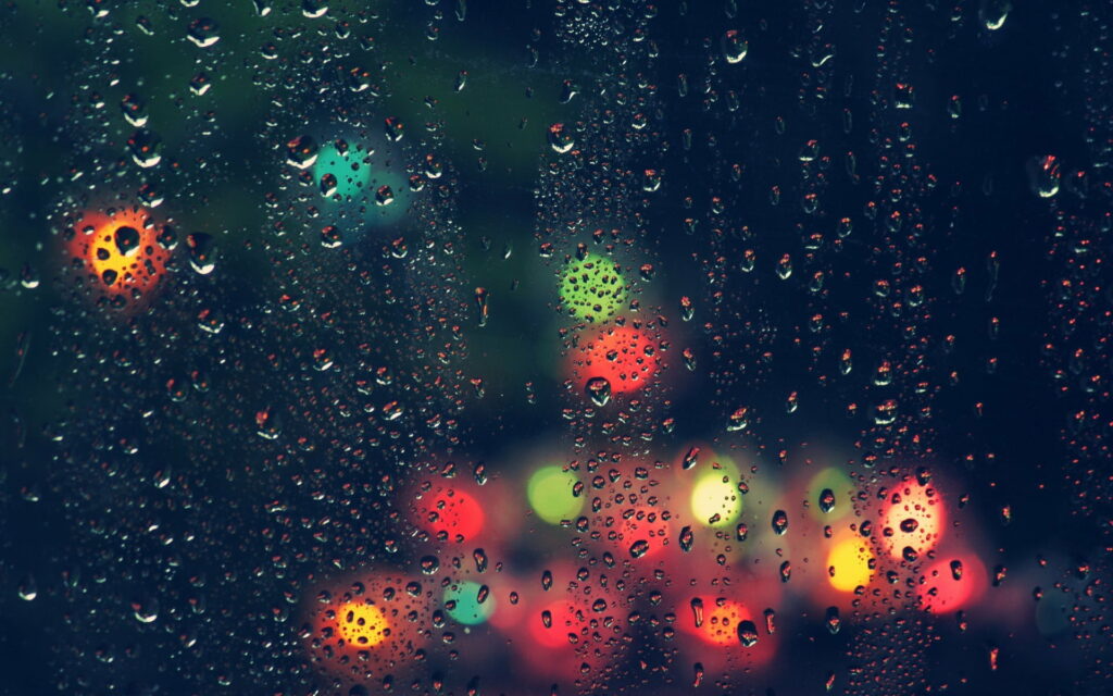 HD wallpaper raindrops on dark window with vibrant red green yellow bokeh lights background