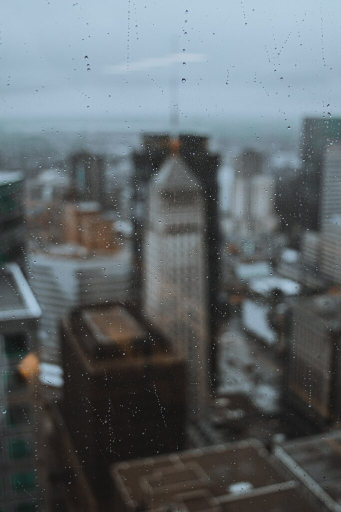 Rainy Cityscape Wallpaper: Blurred Buildings Through Glass Window