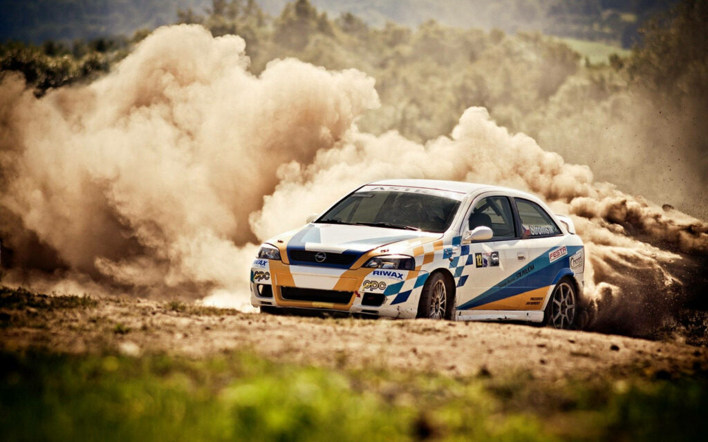 Rally car speeding on rugged dirt track kicking up dust with vibrant decals and green hills background Wallpaper