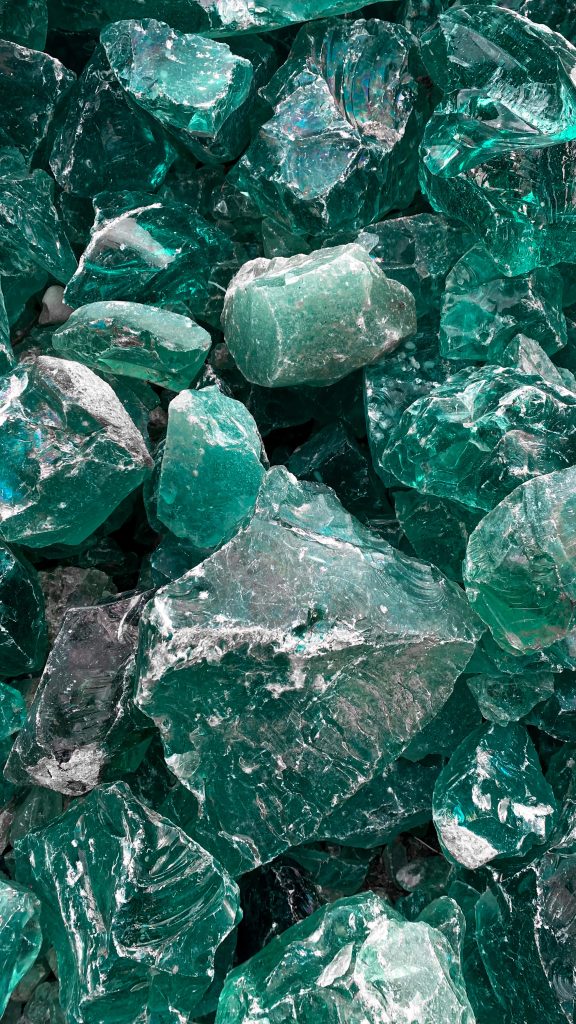 Close-up of rough-cut green gemstone shards textured abstract emerald wallpaper background