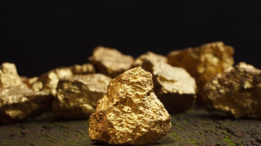Macro shot of jagged gold nuggets on dark textured surface with rich metallic luster background Wallpaper