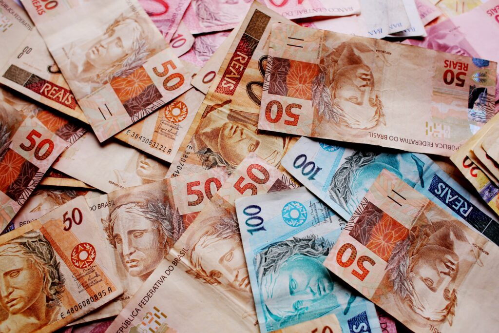 High-angle view of vibrant overlapping 50 and 100 Brazilian Real banknotes wallpaper background