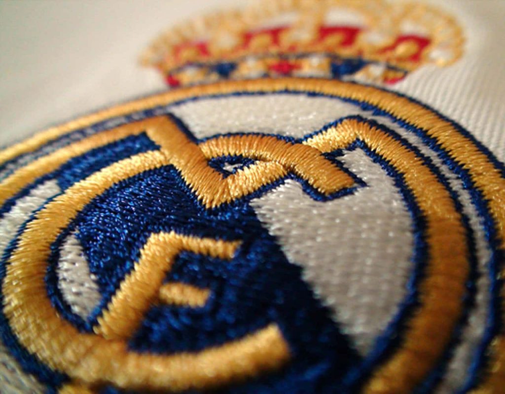 Real Madrid crest macro embroidery wallpaper vibrant gold blue emblem premium style background