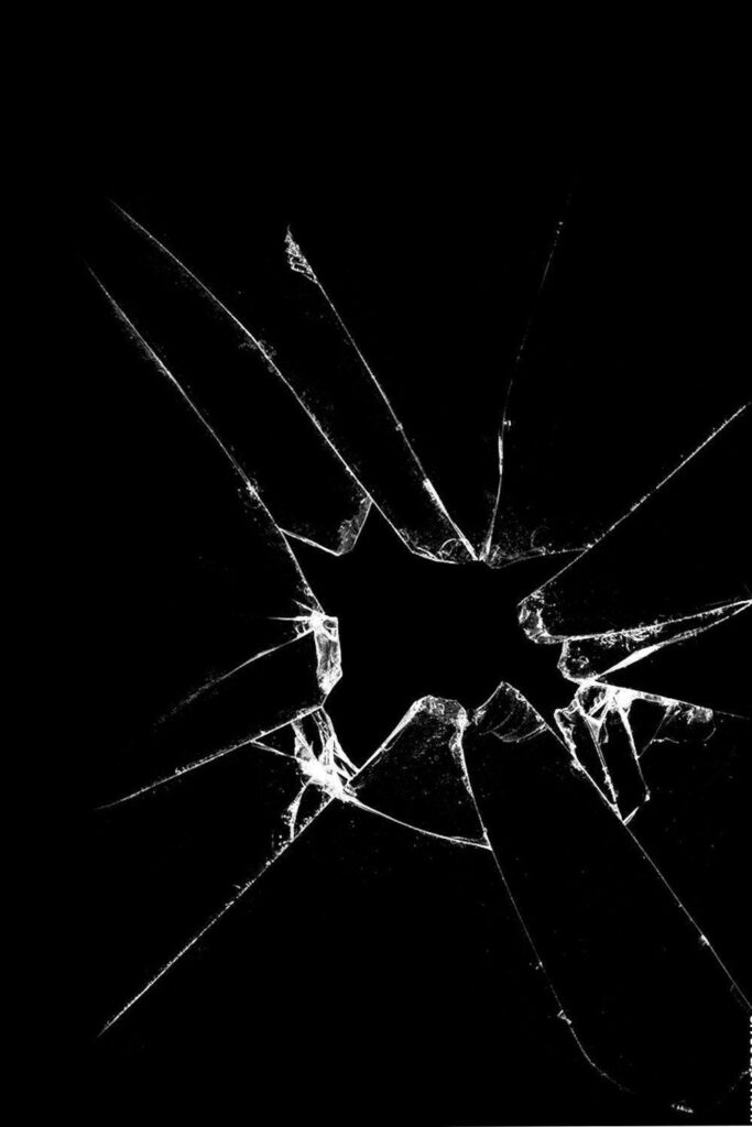 Realistic broken screen wallpaper with central hole on black background dramatic glass crack