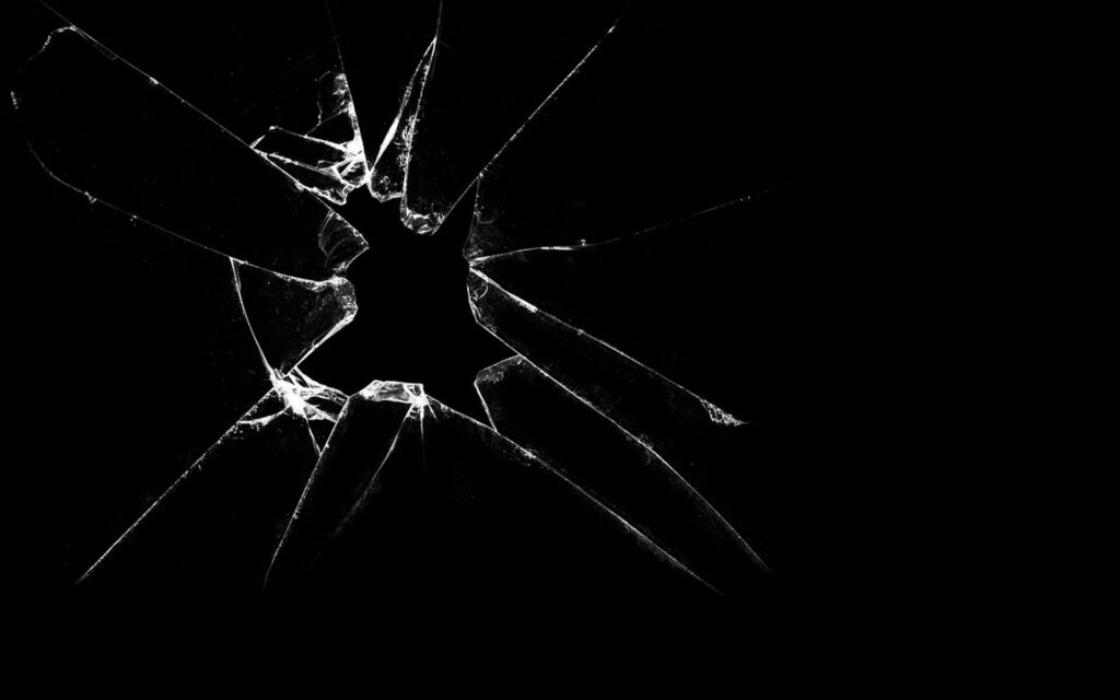 Realistic broken screen wallpaper with sharp shattered glass cracks on deep black background
