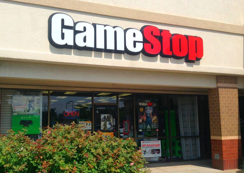 GameStop storefront with red signage open sign and vintage Madden 15 NBA 2K15 posters in daylight Wallpaper