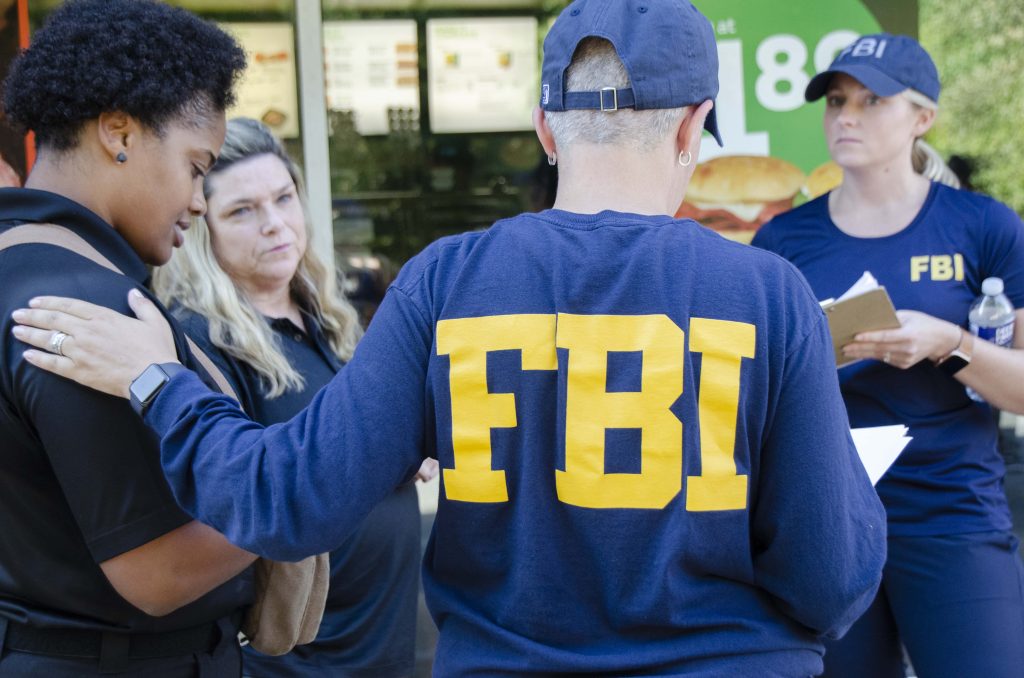 FBI agents in blue shirts comforting civilian outside fast-food restaurant realistic wallpaper