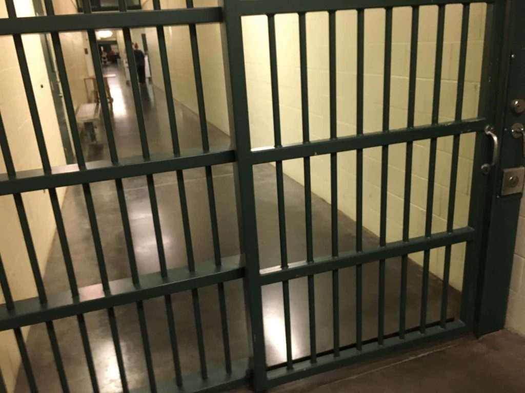 Realistic jail wallpaper with steel bars and sterile prison corridor in somber mood background