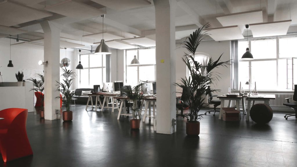 Monochrome open-plan office with industrial lighting and red accents perfect for Zoom background Wallpaper
