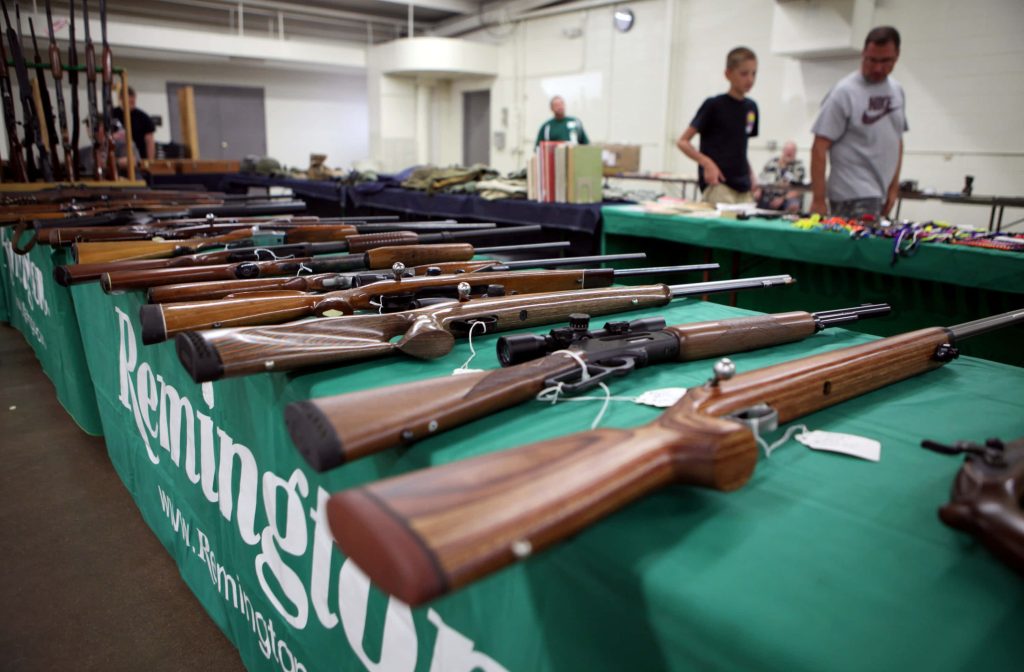 Close-up of rifles with wooden stocks on green Remington table at indoor gun show display Wallpaper