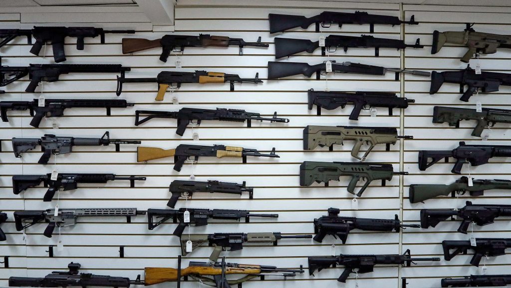 Tactical gun collection on white slatwall with wooden AK rifles modern AR carbines and bullpup firearms Wallpaper