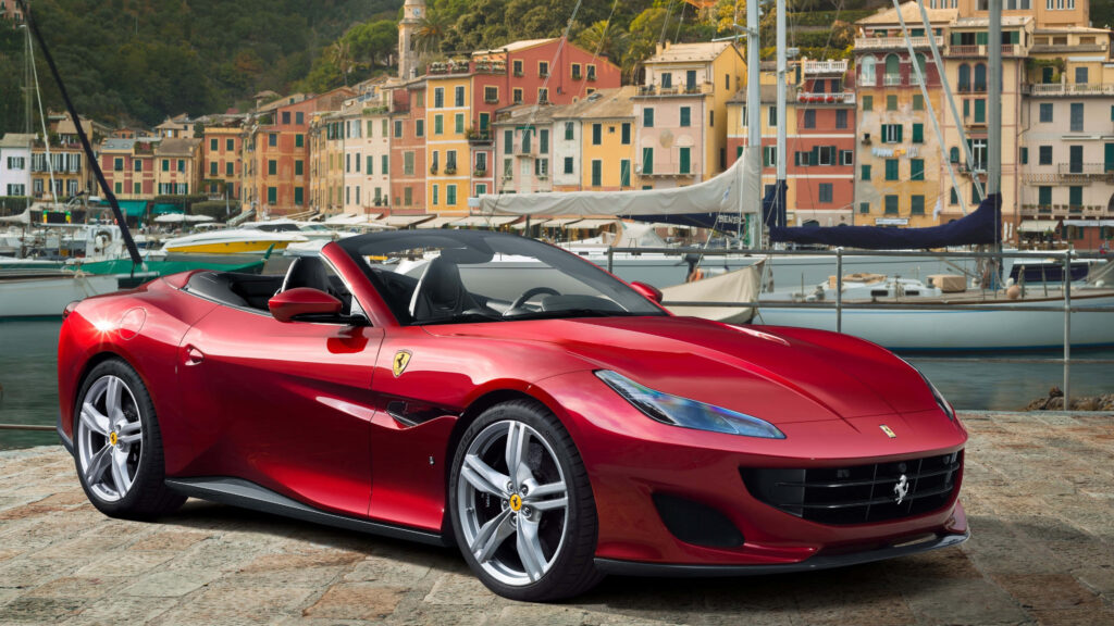 Red 2019 Ferrari Portofino convertible parked by waterfront with classic buildings and boats background Wallpaper