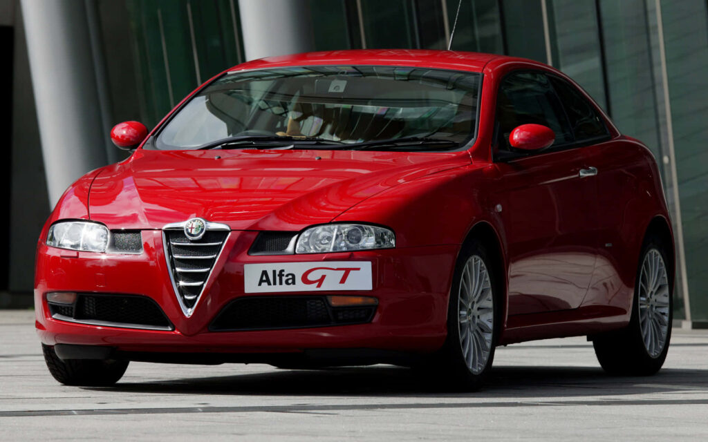 Red Alfa Romeo GT sports car with signature grille and sleek curves in modern setting wallpaper