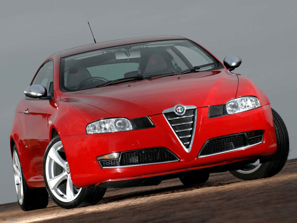 Red Alfa Romeo GT parked outdoors showcasing sleek sporty design in dramatic wallpaper background