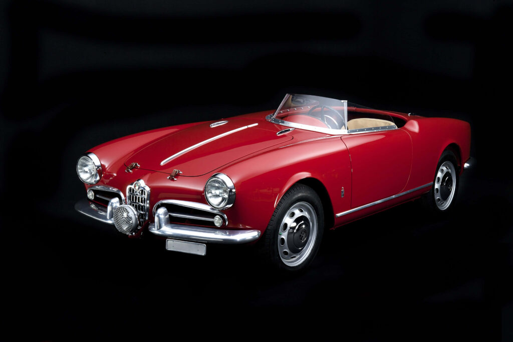 Red Alfa Romeo Spider classic convertible with elegant curves on dark wallpaper background