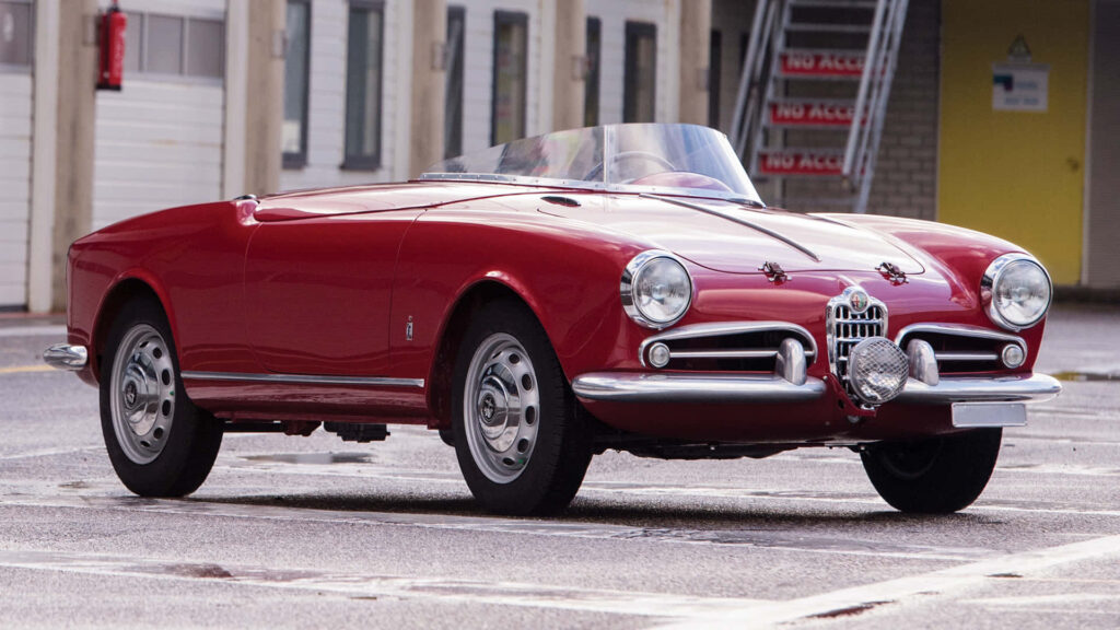 Red Alfa Romeo Spider convertible showcasing retro design and sporty timeless appeal outdoors Wallpaper