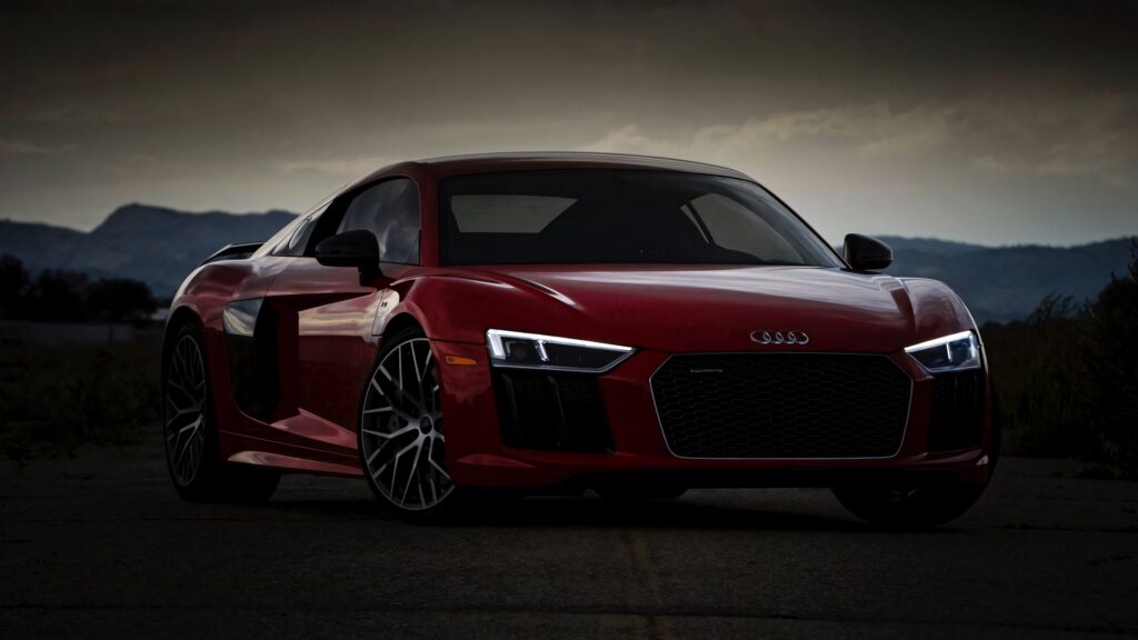 Red Audi sports car with sleek lines and illuminated headlights in dramatic outdoor scene Wallpaper