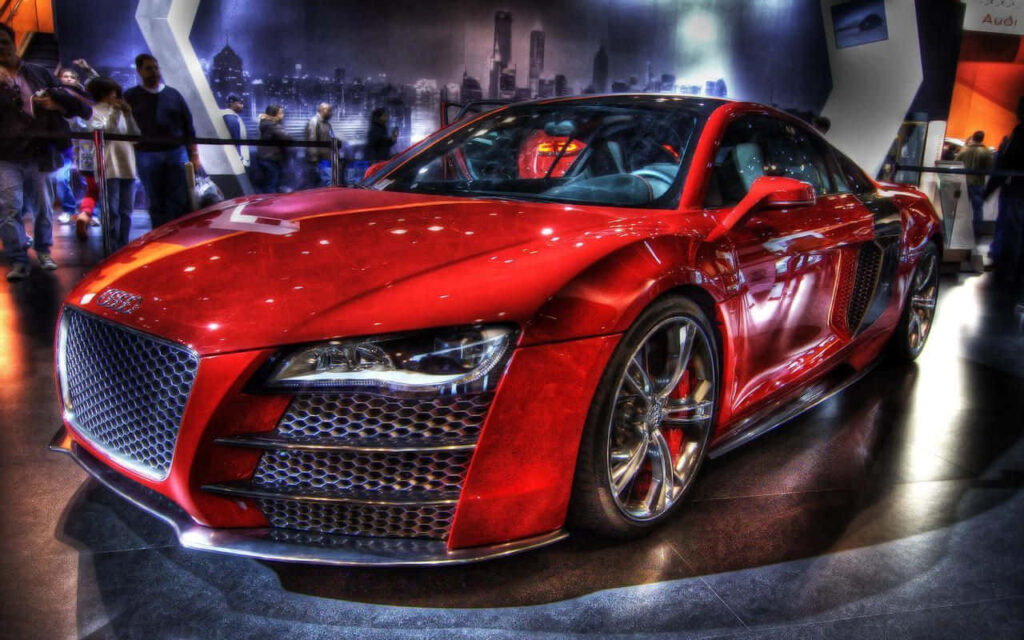 Red Audi street racing car with sleek sporty curves under bright lights cityscape background Wallpaper