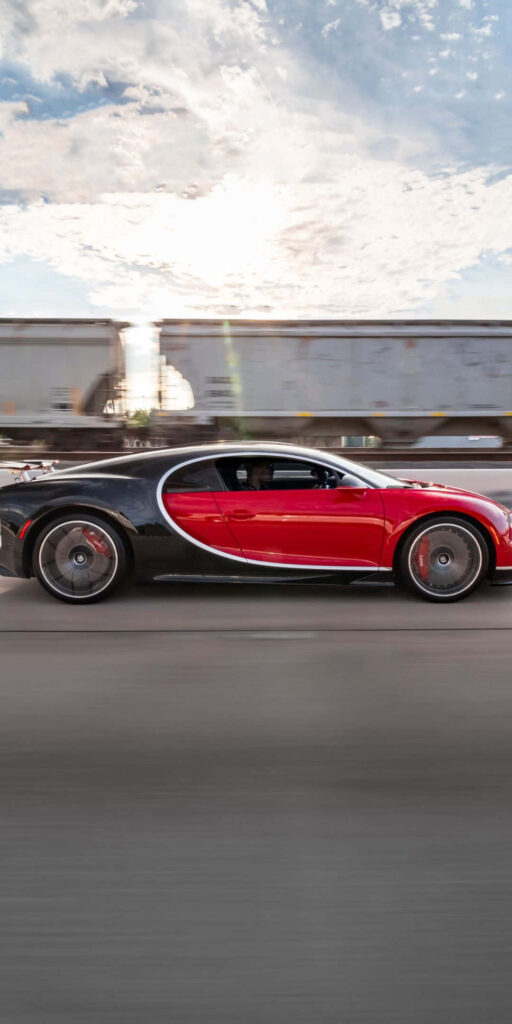 Red Bugatti Chiron speeding on road side view showcasing sleek design and powerful presence Wallpaper