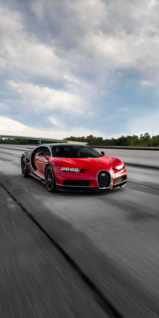 Red Bugatti sports car speeding on concrete road under dramatic sky high-performance wallpaper
