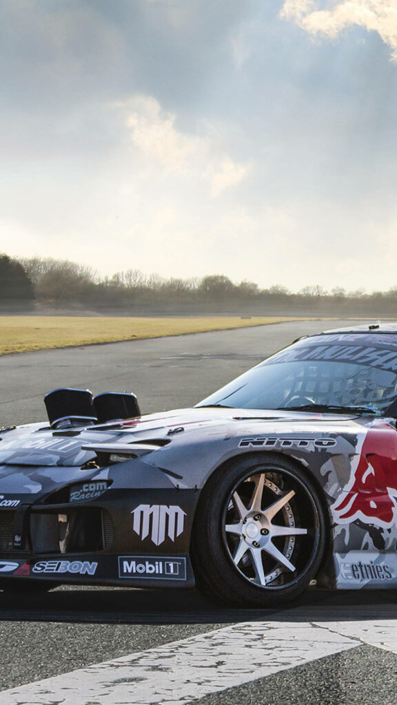 Red Bull Racing car speeding on track with sleek design and branding under clear sky background Wallpaper