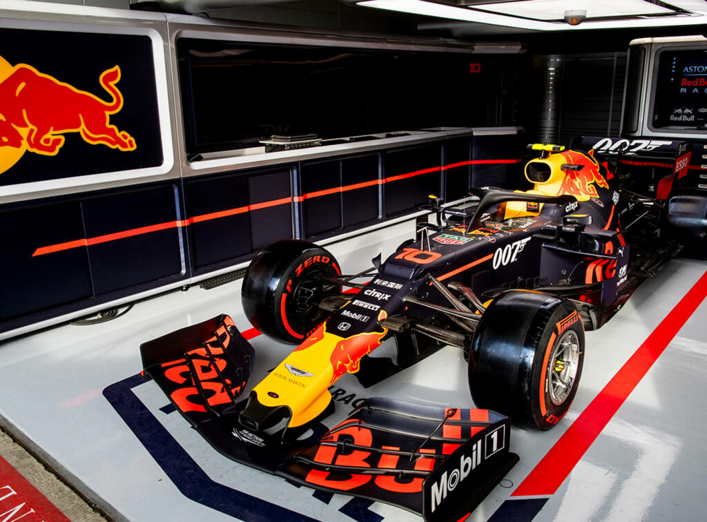 Red Bull Racing Formula 1 garage with car ready for race surrounded by branding and equipment Wallpaper