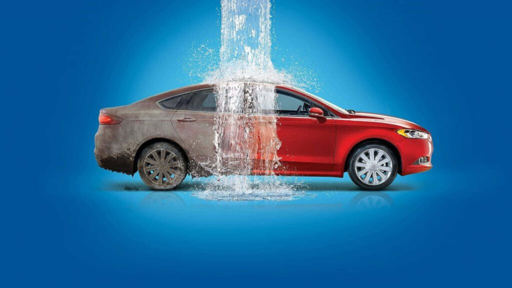 Red car wash with high-pressure water stream revealing shiny clean surface wallpaper background