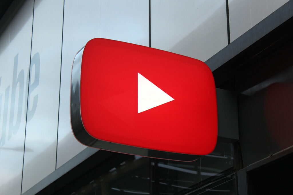 Red YouTube 3D sign with white play button on modern building exterior vibrant tech wallpaper