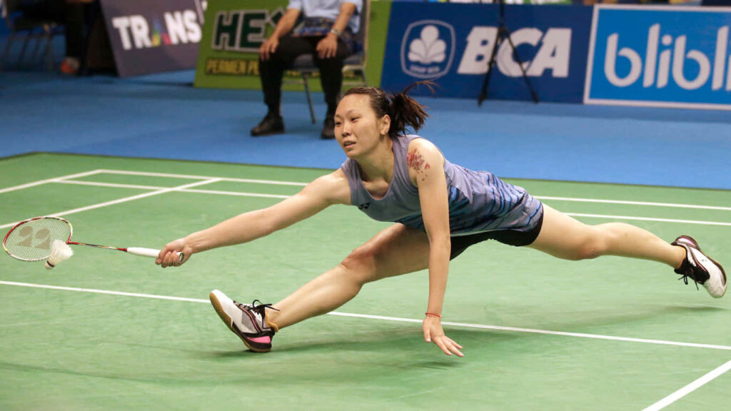 Intense Battle: A Confident Badminton Player Ready to Dominate on the Red Court! Wallpaper