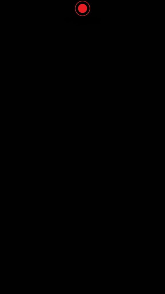Minimalist black HD phone wallpaper with bold red dot camouflaging front camera cutout