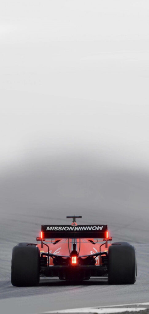 Rear view of red 2022 Ferrari F1 car with glowing tail lights racing on track wallpaper background