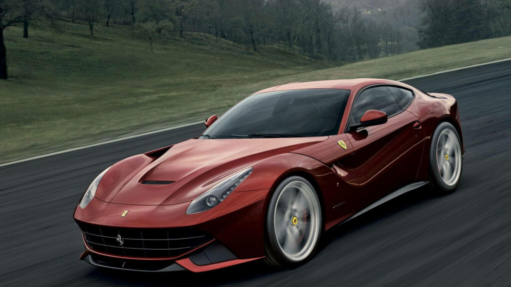 Red Ferrari F12 speeding on scenic road showcasing aerodynamic design and powerful performance Wallpaper