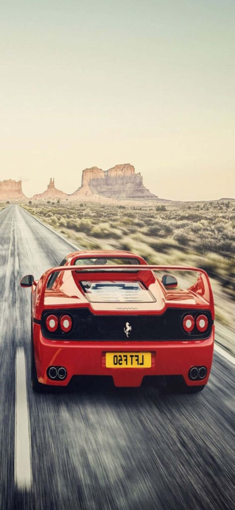 Red Ferrari F50 speeding on desert highway with Max Ferrari rock formations and open sky wallpaper