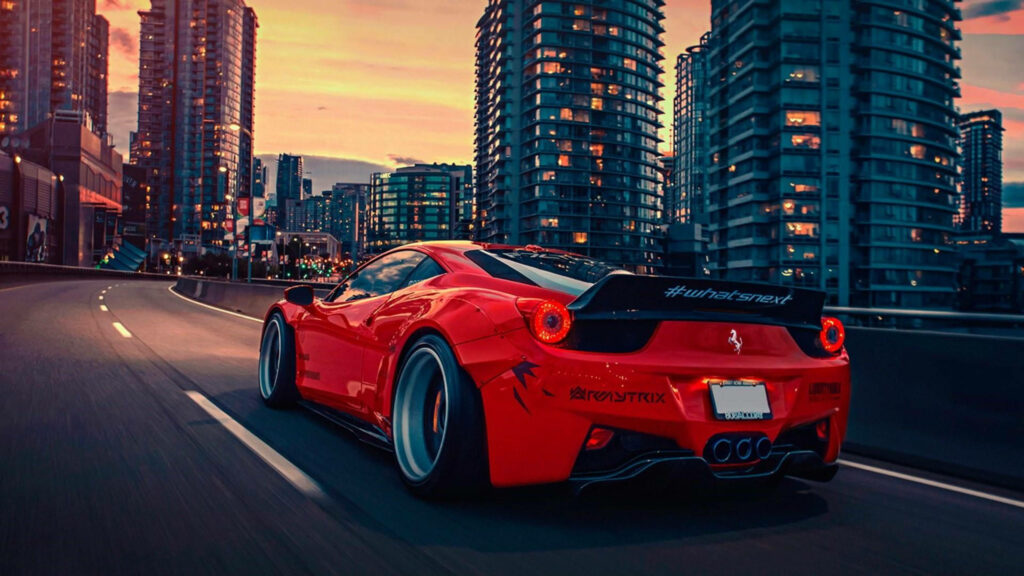 Red Ferrari racing car speeding through vibrant modern cityscape at sunset wallpaper background