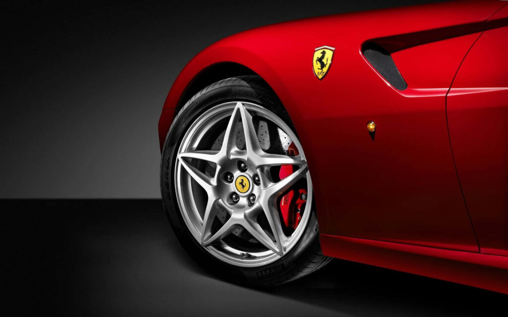 Close-up of red Ferrari sports car showing sleek curves badge and stylish alloy wheel wallpaper