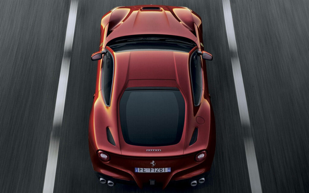 Top-down view of a red Ferrari supercar speeding on highway showcasing power and speed wallpaper