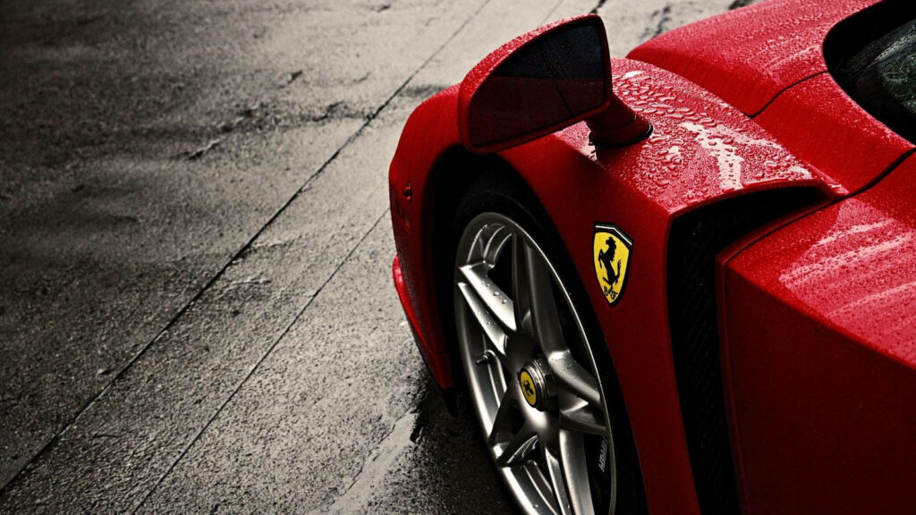 Thrilling Rainy Ride: A Captivating Red Ferrari Speeding through the Wet Streets, Illuminated by Dazzling Headlights Wallpaper