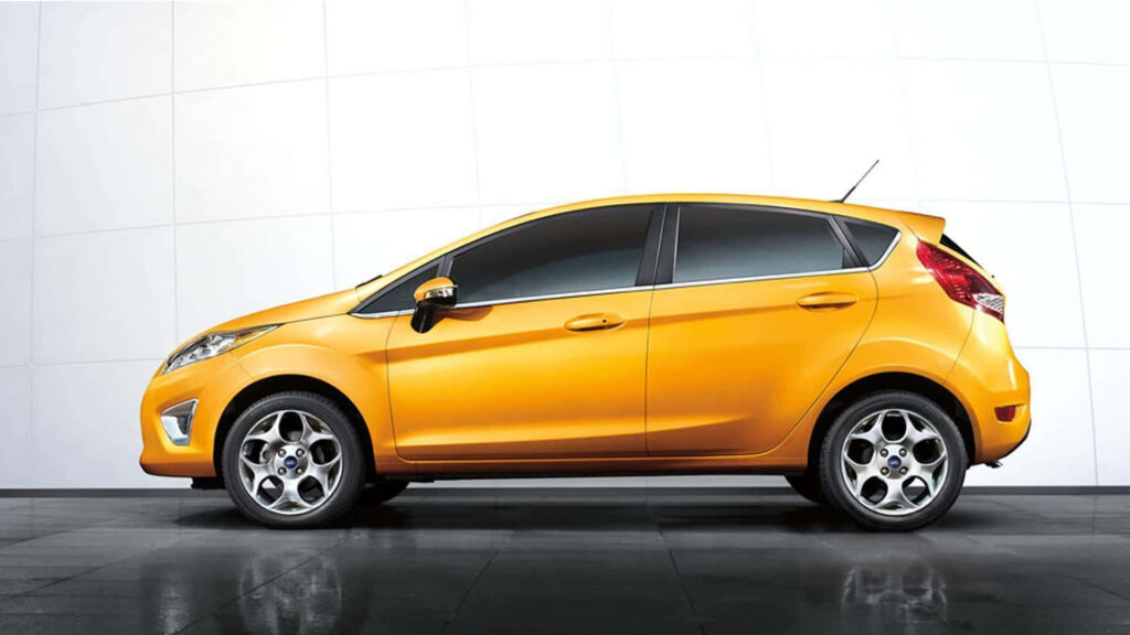 Red Ford Fiesta in motion showcasing sporty design against modern urban wallpaper background