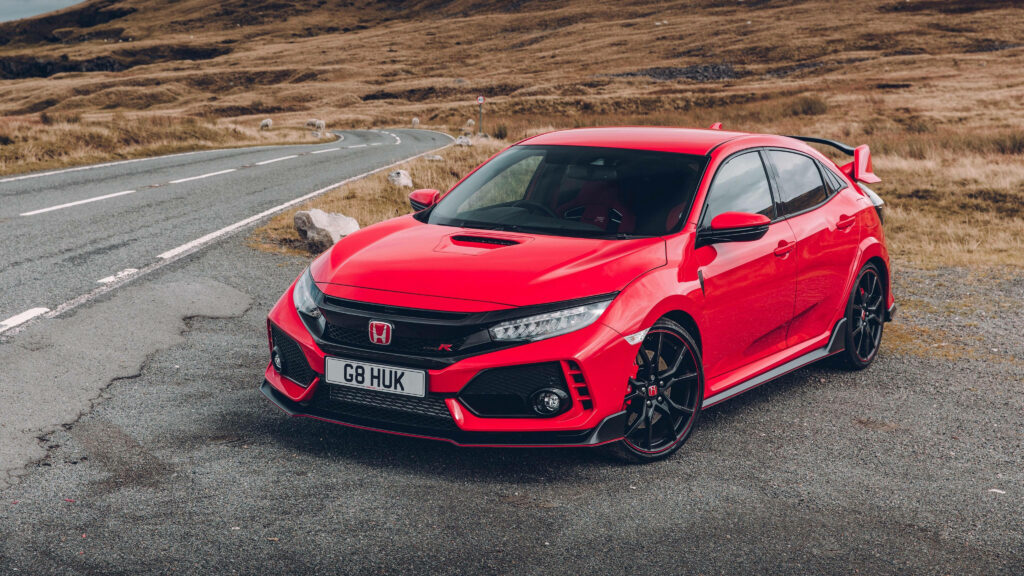 Red Honda Civic parked roadside with scenic winding roads and rugged countryside background Wallpaper
