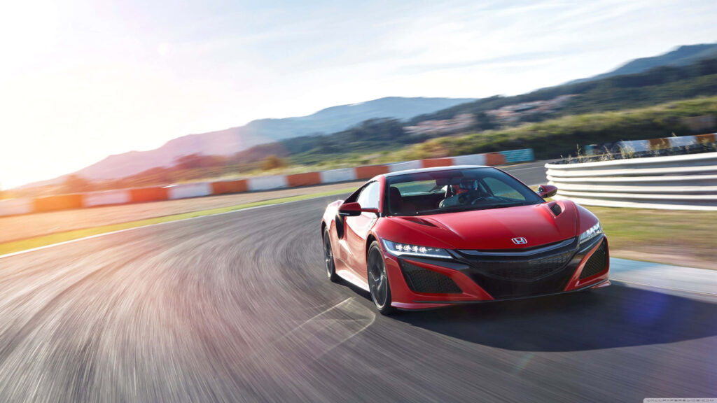 Red Honda NSX speeding on sunlit racetrack with scenic mountain background high-performance car Wallpaper