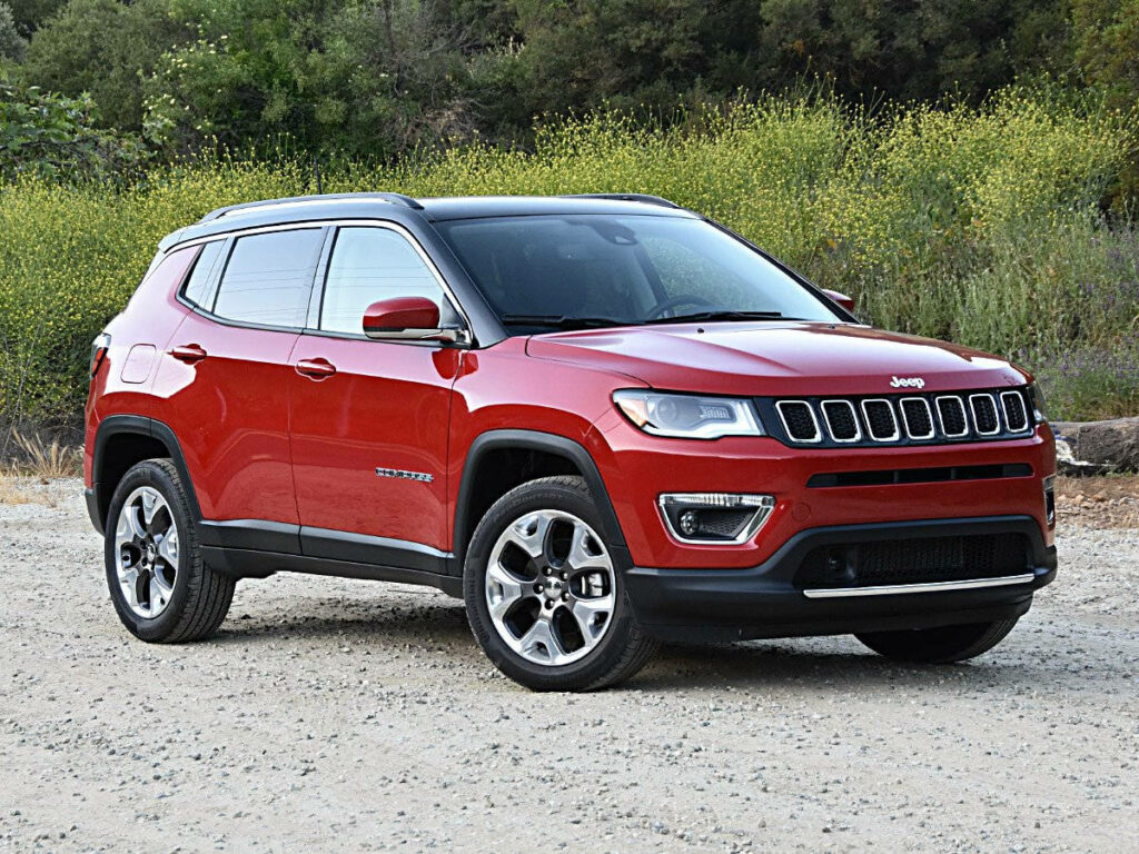 Red Jeep Compass parked on gravel road with green foliage showcasing rugged adventurous design Wallpaper