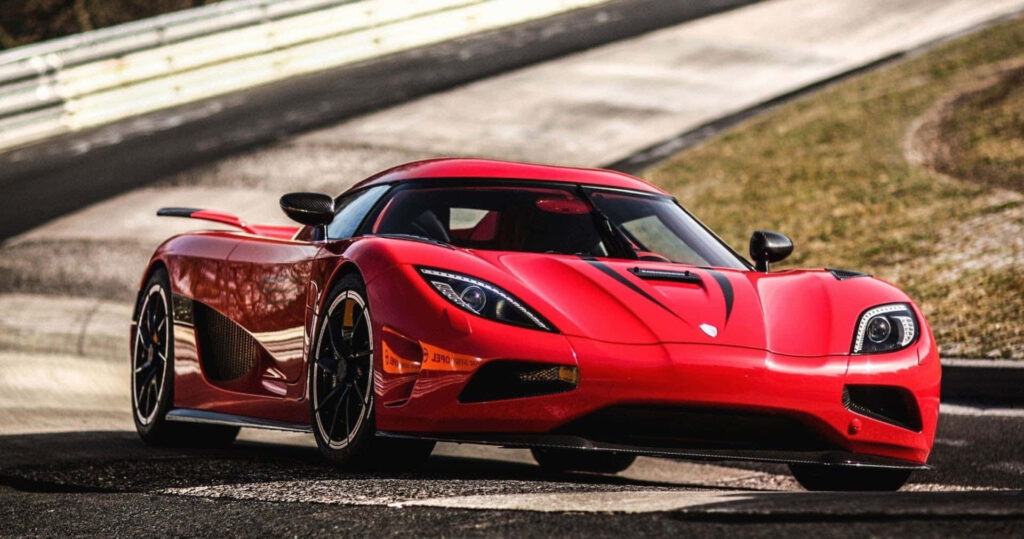 Red Koenigsegg supercar on winding road showcasing sleek design and high performance engineering Wallpaper