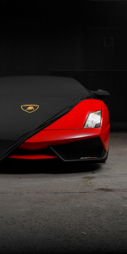 Red Lamborghini sports car front partially covered with black cloth showcasing luxury design wallpaper