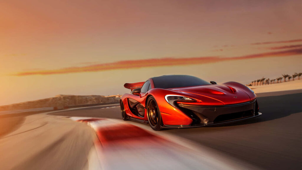 Red McLaren P1 supercar racing at sunset on track showcasing sleek design and high performance Wallpaper