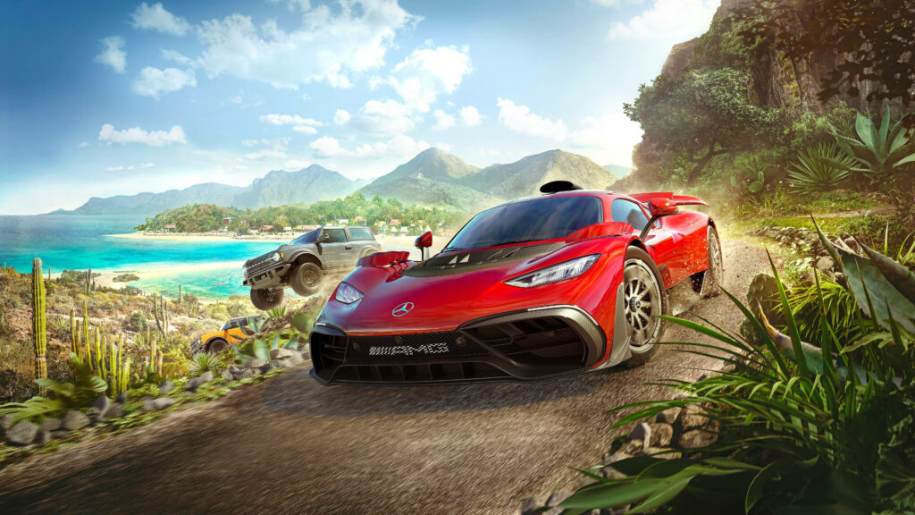 Red Mercedes Benz AMG speeding on coastal road with lush mountains and blue ocean background Wallpaper