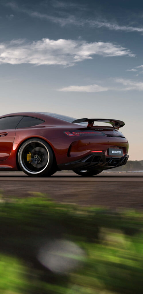 Red Mercedes AMG GT-R speeding on open road with rear wing and scenic natural background wallpaper