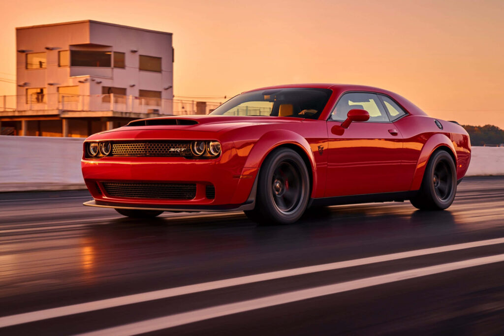 Red muscle car speeding on sunset race track powerful elegant wallpaper background image