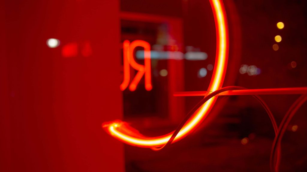 4K red neon wallpaper glowing curved light tube with blurred Cyrillic letter Я background